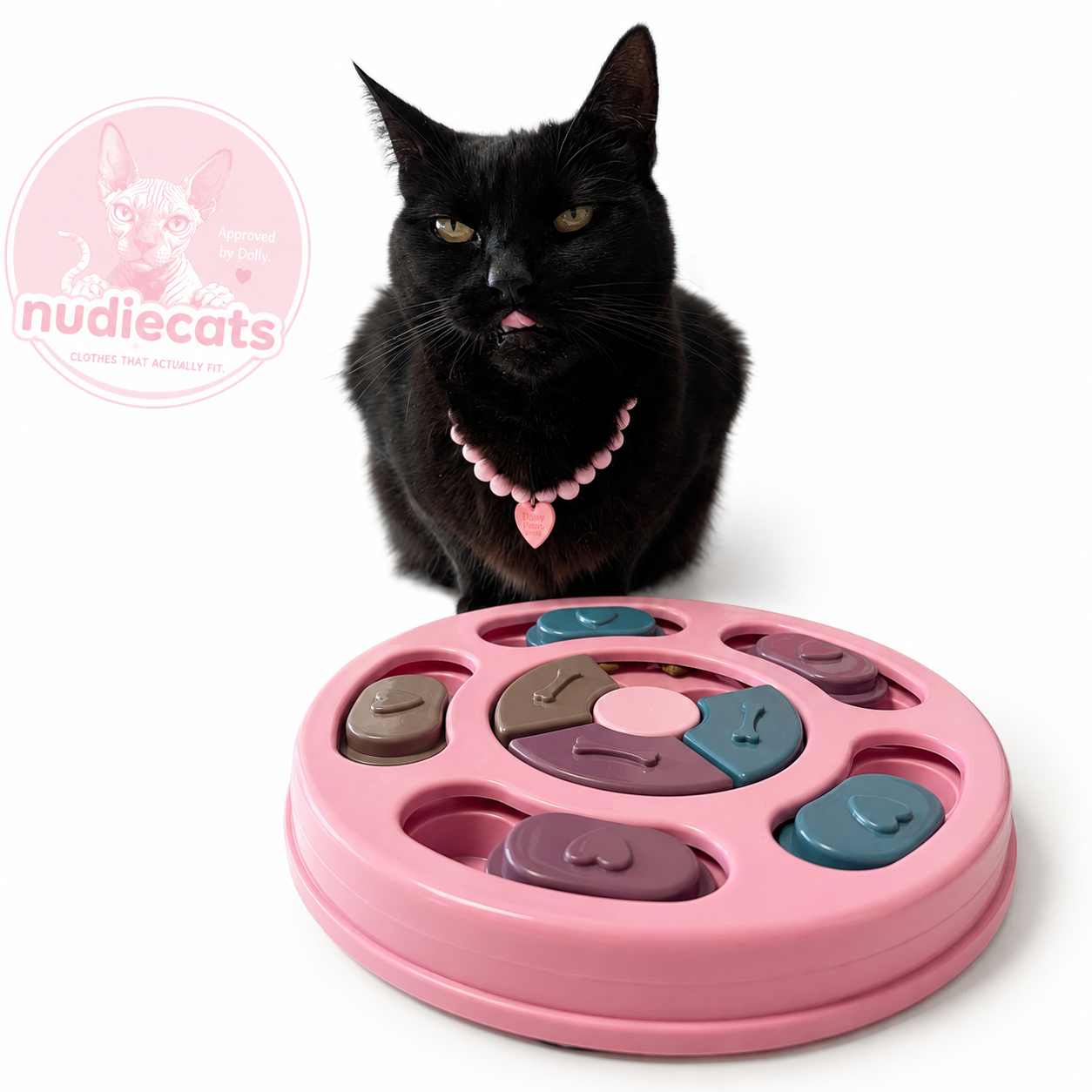 Snack Attack Cat Puzzle Feeder in Strawberry Milk; lifestyle view featuring a black cat behind the pink interactive feeder